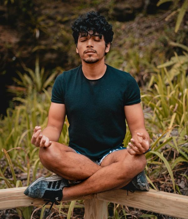 A person meditating peacefully outdoors, surrounded by nature and tranquility.
